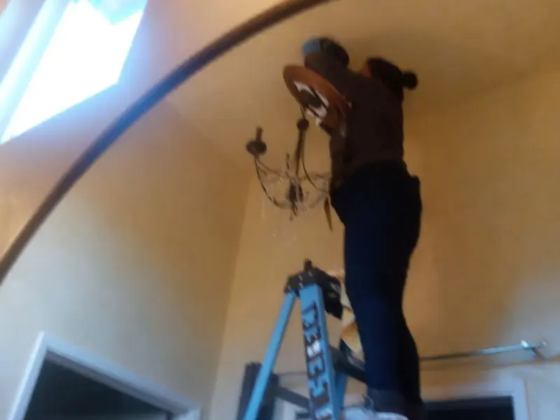 Electrician installing a chandelier in a Chazy residence